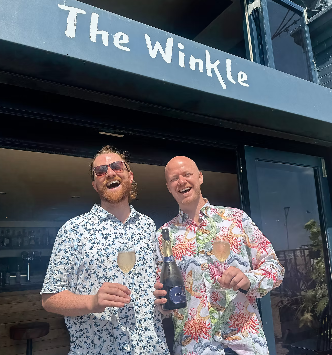 Owners Owen & PJ with a glass of fizz outside The Winkle